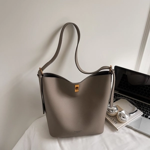 Détail du sac seau en cuir taupe avec texture grainée et fermoir rotatif en métal doré