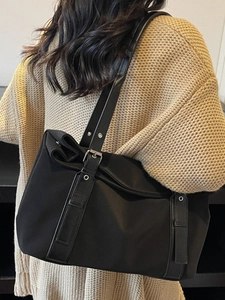 Grand sac à bandoulière classique en daim noir porté par un mannequin en mode lifestyle