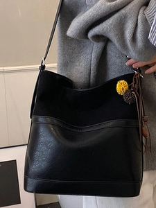 Vintage black oversized bucket bag with contrast textures and decorative plush charms