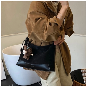 Detail of suede and leather patchwork shoulder bag with a brown teddy bear pendant
