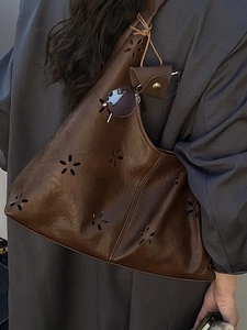 Brown vintage leather shoulder bag with laser-cut floral patterns and small side pouch