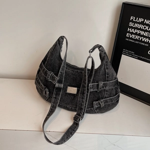 Detailed view of black denim crossbody bag featuring metal logo and decorative buckle straps