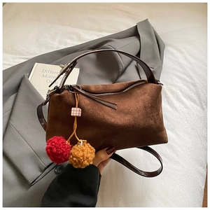 Detail of vintage brown suede shoulder bag with plush pom-poms and leather handle