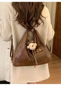 Detailed view of dark brown retro leather tote bag with teddy bear charm and tassels
