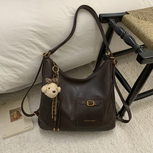 Detail of dark brown faux leather tote bag with small buckle pocket and plush bear charm