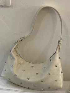 Schicke cremefarbene Hobo-Tasche mit silbernen Metallnieten und verstellbarem Riemen