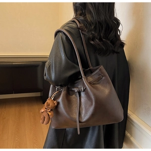 Detail view of vintage dark brown leather tote bag with stylish plush bear charm detail