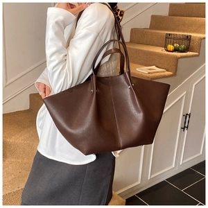Detailed macro view of dark brown leather tote bag with wing design and vertical seam