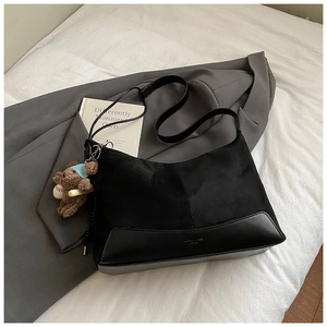 Detail of black patchwork shoulder bag with suede texture and cute teddy bear charm