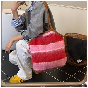 Close-up of fluffy red and pink striped knit tote bag with Bonne journée embroidery