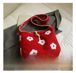 Detail shot of red plush tote bag with white flower embroidery and soft textured fabric
