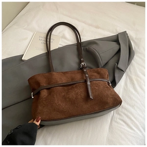 Detailed close-up of dark brown suede tote bag with leather strap and silver buckle