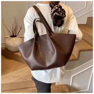 Detail of a large dark brown PU leather tote bag with silver rivets and elegant wing shape