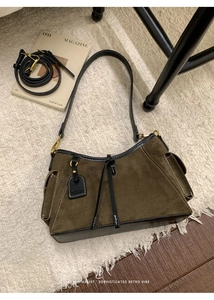 Detail der olivgrünen Wildleder-Schultertasche mit schwarzem Lederbesatz und weißen Nähten