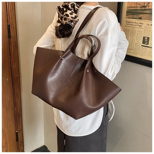 Detail view of large dark brown bat-shaped tote bag showing soft synthetic leather texture