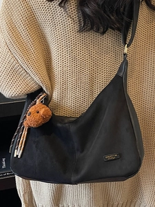Sac bandoulière vintage noir minimaliste avec breloque ours pour femme sur tricot beige