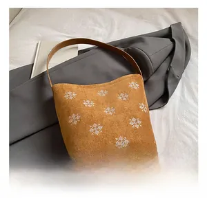 Dettaglio della borsa tote in pelle scamosciata marrone con ricamo a fiocco di neve e tracolla