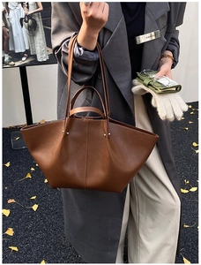 Brown leather trapezoid tote bag with wing folding structure shown in street photography