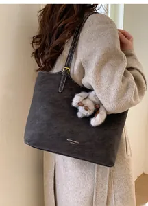 Detail view of charcoal suede tote bag with contrast stitching and plush dog charm