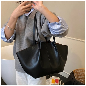 Close-up of minimalist black tote bag with smooth faux leather texture and dual shoulder straps