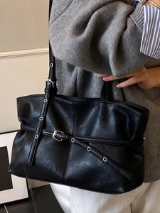 Minimalist black leather tote bag with silver grommets and buckle straps for women
