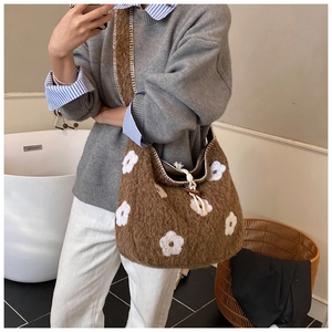 Detailed close-up of brown plush shoulder bag with white flower embroidery and drawstring