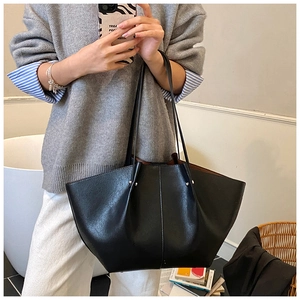 Detail view of large black bat-shaped tote bag with matte leather finish and metal rivets