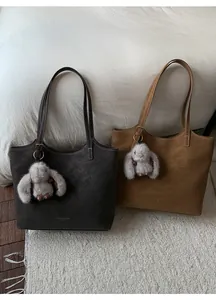 Detail view of large brown faux leather tote bags with cute plush rabbit pendants