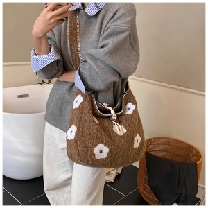 Detail of plush tote bag with flower embroidery, drawstring closure, and wood button accent
