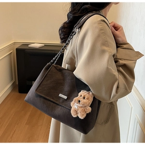Detailansicht der dunkelbraunen Wildleder-Schultertasche mit Metallkette und Bären-Anhänger