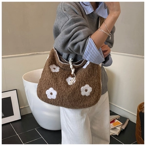 Detail of plush tote bag showing flower embroidery and soft white drawstring closure
