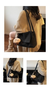 Detail of minimalist black tote bag featuring a cute brown plush bear charm and leather strap