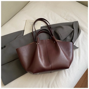 Deep burgundy leather tote bag with unique wing structure and protective metal feet detail