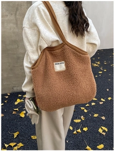 Detail view of large brown fuzzy tote bag with SEEYOU label and thick woven strap