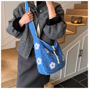 Detail of blue plush tote bag with white flower embroidery and wooden toggle closure