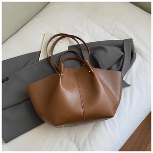 Detailed macro view of brown matte leather tote featuring silver rivets and wing design