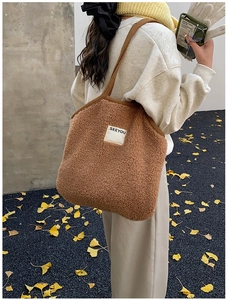 Detail of caramel faux shearling tote bag with SEEYOU label held by a model outdoors