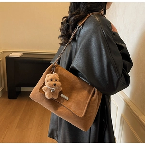 Detailaufnahme der braunen Wildledertasche mit Goldkette und Plüschbär-Anhänger