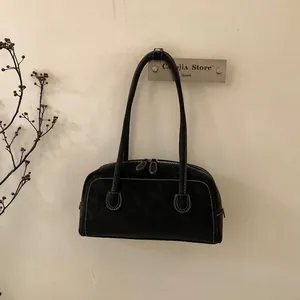 Detailed close-up of a black Boston bag with white contrast stitching and dual zippers