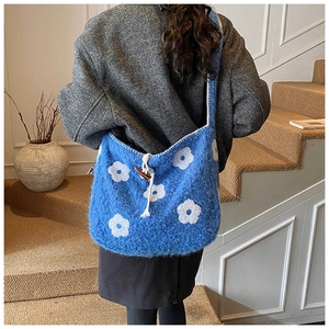 Detail of blue plush tote bag with white flower embroidery and wooden toggle closure