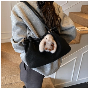 Detail einer schwarzen Wildleder-Tote-Bag mit Kontrastnähten und Hasen-Anhänger