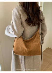 Borsa hobo minimalista in pelle scamosciata marrone indossata da una modella