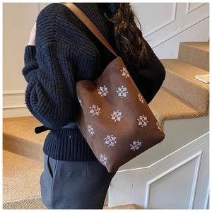 Borsa tote marrone con ricamo a fiocco di neve portata a spalla in un interno minimalista