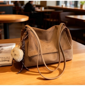 Close-up of brown suede tote bag featuring plush charm detail and fine texture
