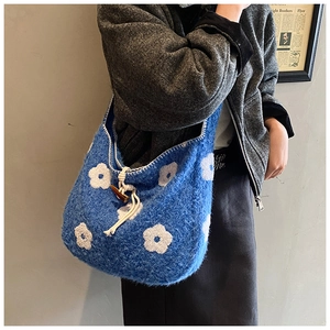 Close-up of blue plush shoulder bag with floral embroidery and wooden button closure