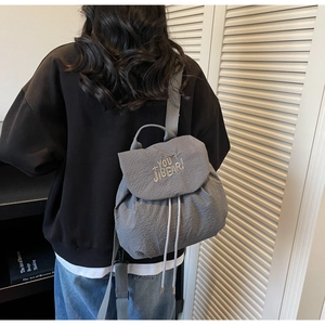 Detail view of gray waffle-texture drawstring backpack with embroidered letter design