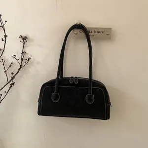 Detail view of black faux suede underarm bag with white contrast stitching and dual zippers
