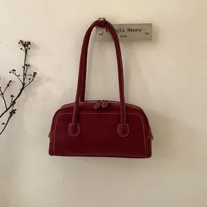 Detailed view of dark red suede-style shoulder bag with elegant white contrast stitching