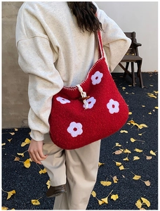 Close-up of red knit tote bag featuring white floral embroidery and wood horn buckle