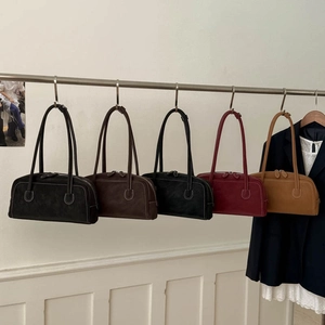 Five minimalist matte suede shoulder bags in autumn colors hanging on a display rack